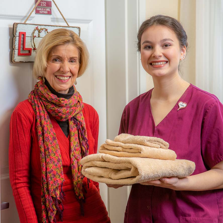 A team member delivering fresh linens to a resident at Ashwood Meadows